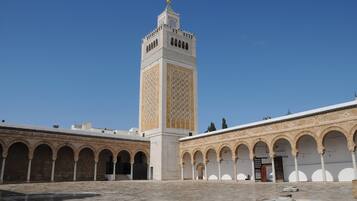 A courtyard with a tall tower featuring intricate tile work and a dome.