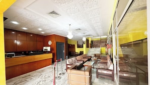 A hotel lobby with a reception desk, seating area, and a staircase leading to an upper floor. - Hotel TEJ (Tunis)