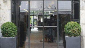 The entrance to HOTEL DE PARIS with a glass door, framed by stone architecture and two large potted plants. - Hôtel de Paris (Besancon)