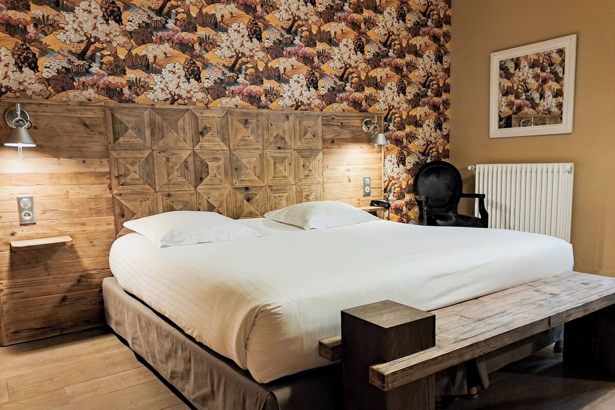 A bedroom with a wooden headboard, a bed with white linens, a bedside table with a lamp, and a radiator.