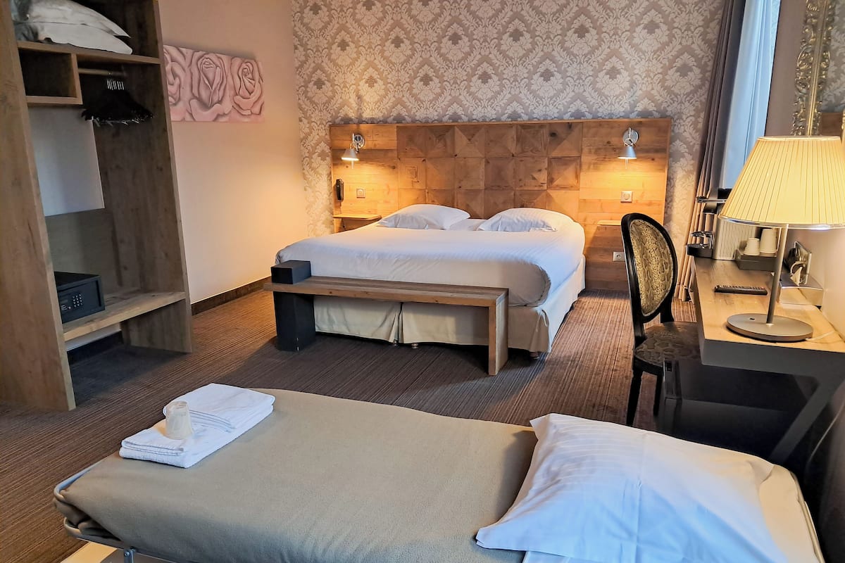 A hotel room with a bed, bedside table, lamp, and a wooden headboard.