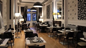 A dining area with tables set for service, elegant wall patterns, and large pendant lights. - Hôtel de Paris (Besancon)