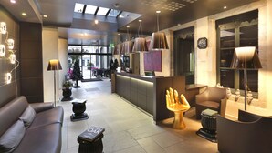 A modern hotel lobby with a reception desk, seating area, and a view of the street. - Hôtel de Paris (Besancon)