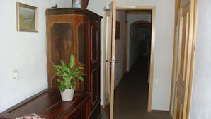 Un corridoio con un armadietto in legno, una pianta in vaso e una porta che dà su un'altra stanza.