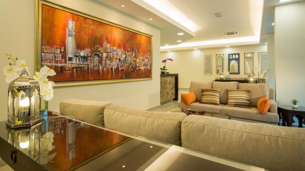 A modern living room with a large painting, a sofa set, and a glass coffee table. - Humaira Hotel (Tanah Merah)