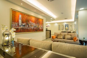 A modern living room with a large painting, a sofa set, and a glass coffee table.