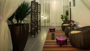 A hallway with a striped rug, wicker furniture, and a potted plant. - Humaira Hotel (Tanah Merah)
