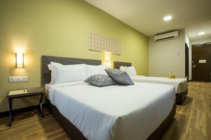 A hotel room with two beds, a nightstand, a wall-mounted air conditioner, and a decorative wall piece.
