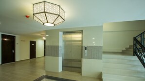 A spacious lobby with a modern elevator, a staircase, and a decorative light fixture. - Humaira Hotel (Tanah Merah)
