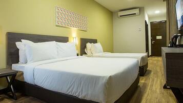 Habitación de hotel con dos camas, un escritorio, un televisor y una planta.
