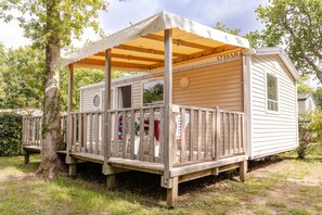 A small wooden cabin with a covered porch, a window, and a door. - Camping Les Chèvrefeuilles (Royan)