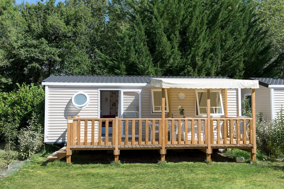 A mobile home with a wooden deck and a covered porch.