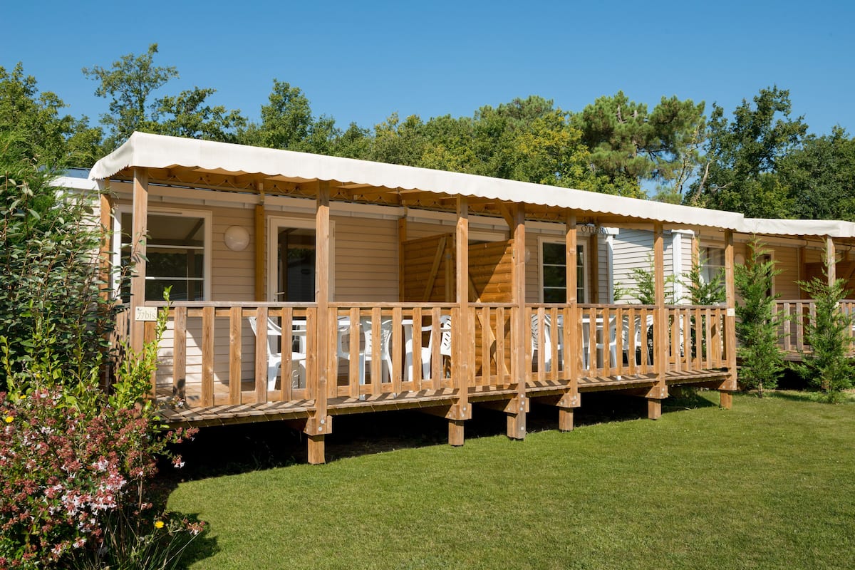 A wooden cabin with a covered porch and a number "77" sign.