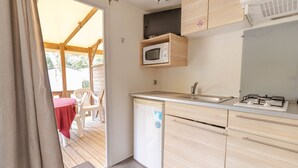 A compact kitchen with a microwave, sink, and a small refrigerator. - Camping Les Chèvrefeuilles (Royan)