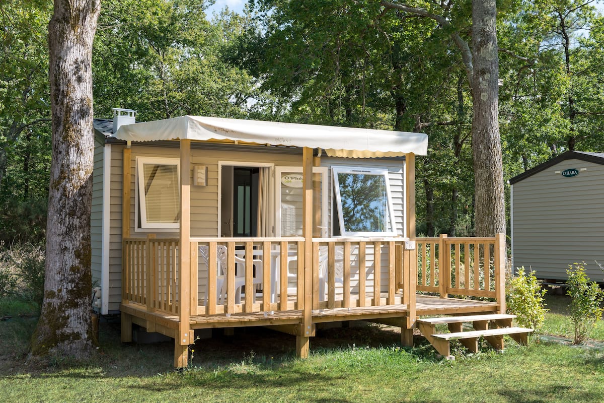 A small wooden cabin with a porch, a covered window, and a door.