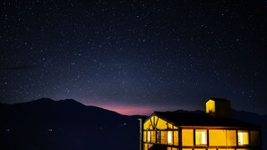 A building with multiple windows and a balcony, surrounded by a mountainous landscape under a starry night sky. - Sheepman Villa (Ren'ai)