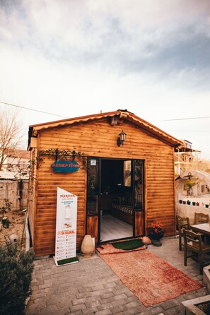 A wooden building with a reception sign, a signboard, and a brick-paved entrance. - Maron Stone House (Nevsehir)