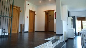 Un interior espacioso con una escalera que sube a un segundo piso, puertas de madera y un radiador blanco.