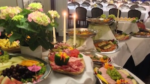 A buffet table with various food items, including fruits, vegetables, and meats, arranged on trays and plates. - Schlosspark-Hotel Hof von Oldenburg (Rastede)