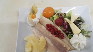 A plate with various fruits and vegetables, including pineapple, red currants, and a salad with lettuce and a raspberry. - Schlosspark-Hotel Hof von Oldenburg (Rastede)