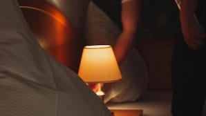 A dimly lit room with a bed, a bedside lamp, and a person standing by the bed. - Schlosspark-Hotel Hof von Oldenburg (Rastede)
