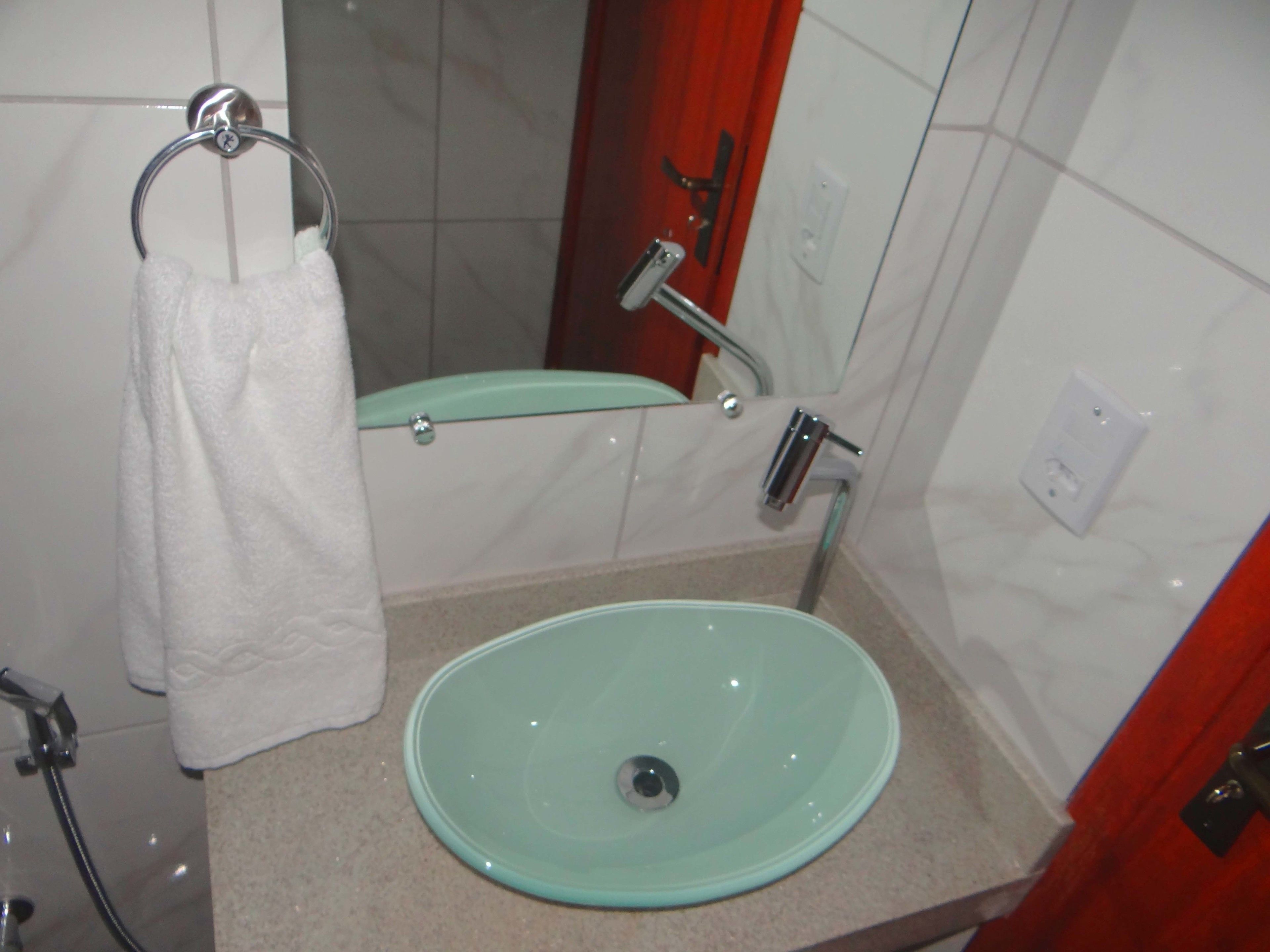 A bathroom with a glass sink, a towel rack, and a shower.