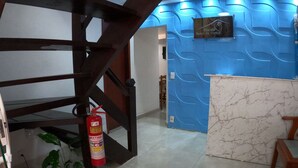 Un área de recepción con pared azul, mostrador de mármol y un extintor en el suelo.