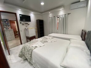 Une chambre d’hôtel avec un lit, une télévision, une armoire et un bureau.