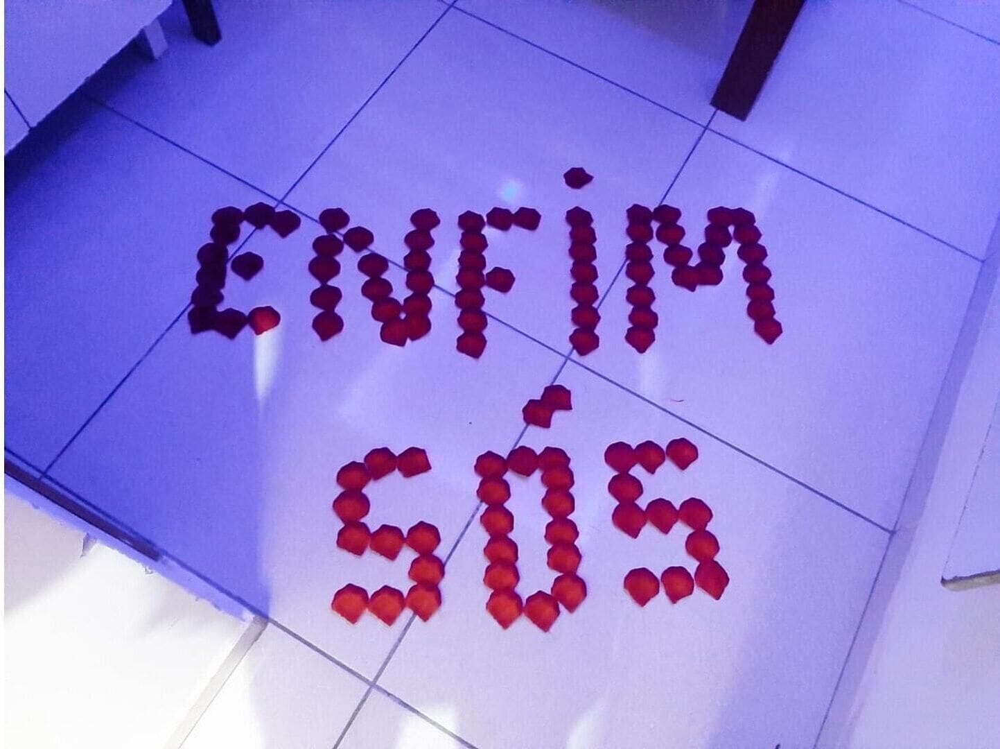 A floor with red rose petals arranged to spell out "Enfim 50s".