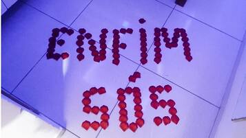 A floor with red rose petals arranged to spell out "Enfim 50s".