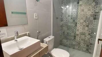 A modern bathroom with a large sink, toilet, and glass shower enclosure.