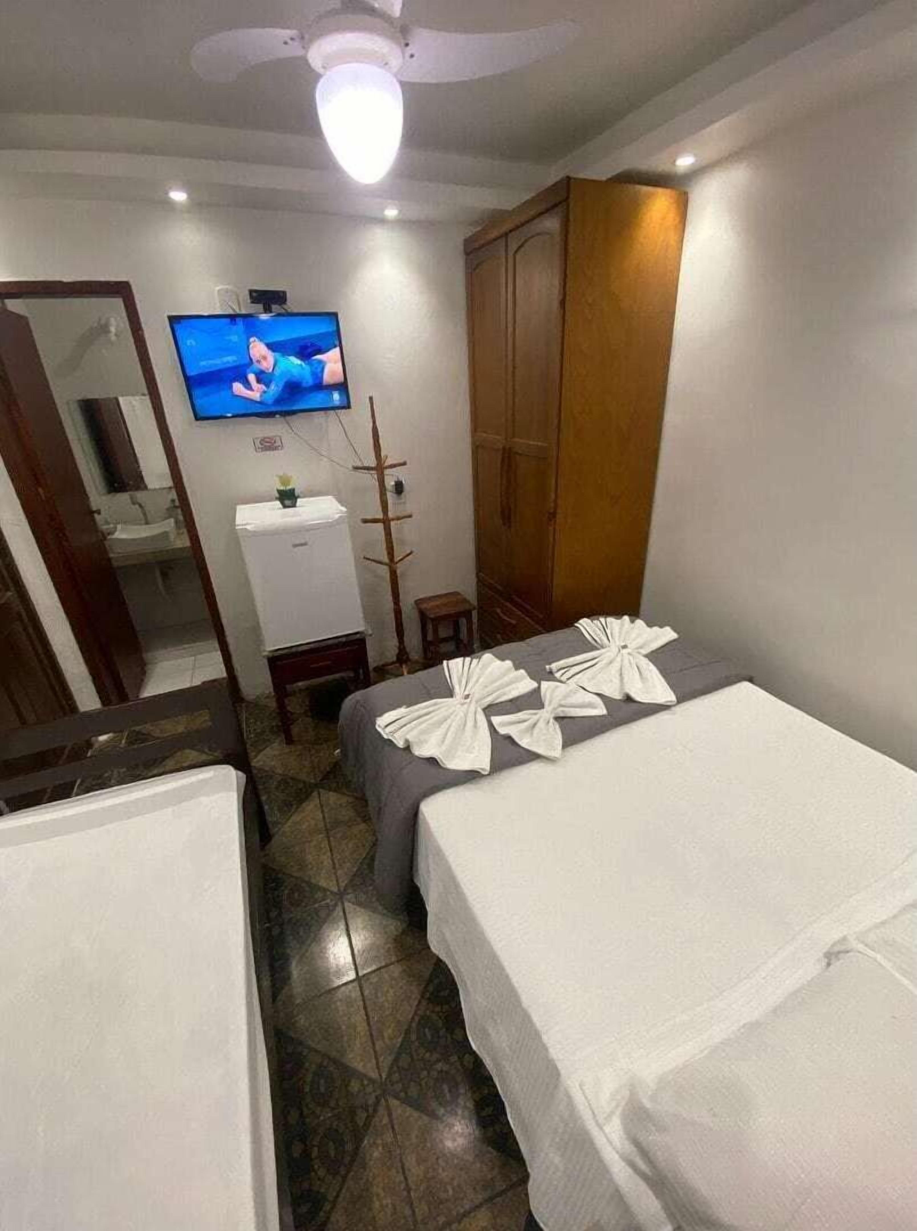 Una habitación de hotel con dos camas, un televisor, un armario y un mueble pequeño.