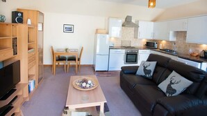 A compact living space with a kitchenette, a dining area, and a seating area with a sofa and a TV.