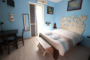 A bedroom with a bed, a desk, a chair, a bench, a mirror, and a map on the wall. - B&B San Leone (Agrigento)