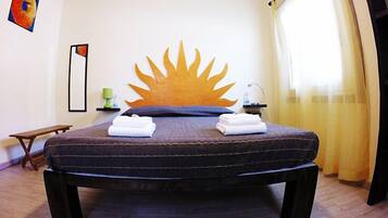 Una cama con cabecera en forma de sol, una mesita de noche y un banco.