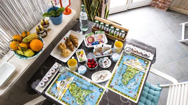 A breakfast setup with a variety of food items, including fruits, pastries, and beverages, arranged on a table with a map-themed placemat. - B&B San Leone (Agrigento)
