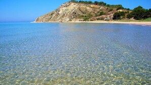 A beach with clear shallow waters and a rocky hill in the background. - B&B San Leone (Agrigento)