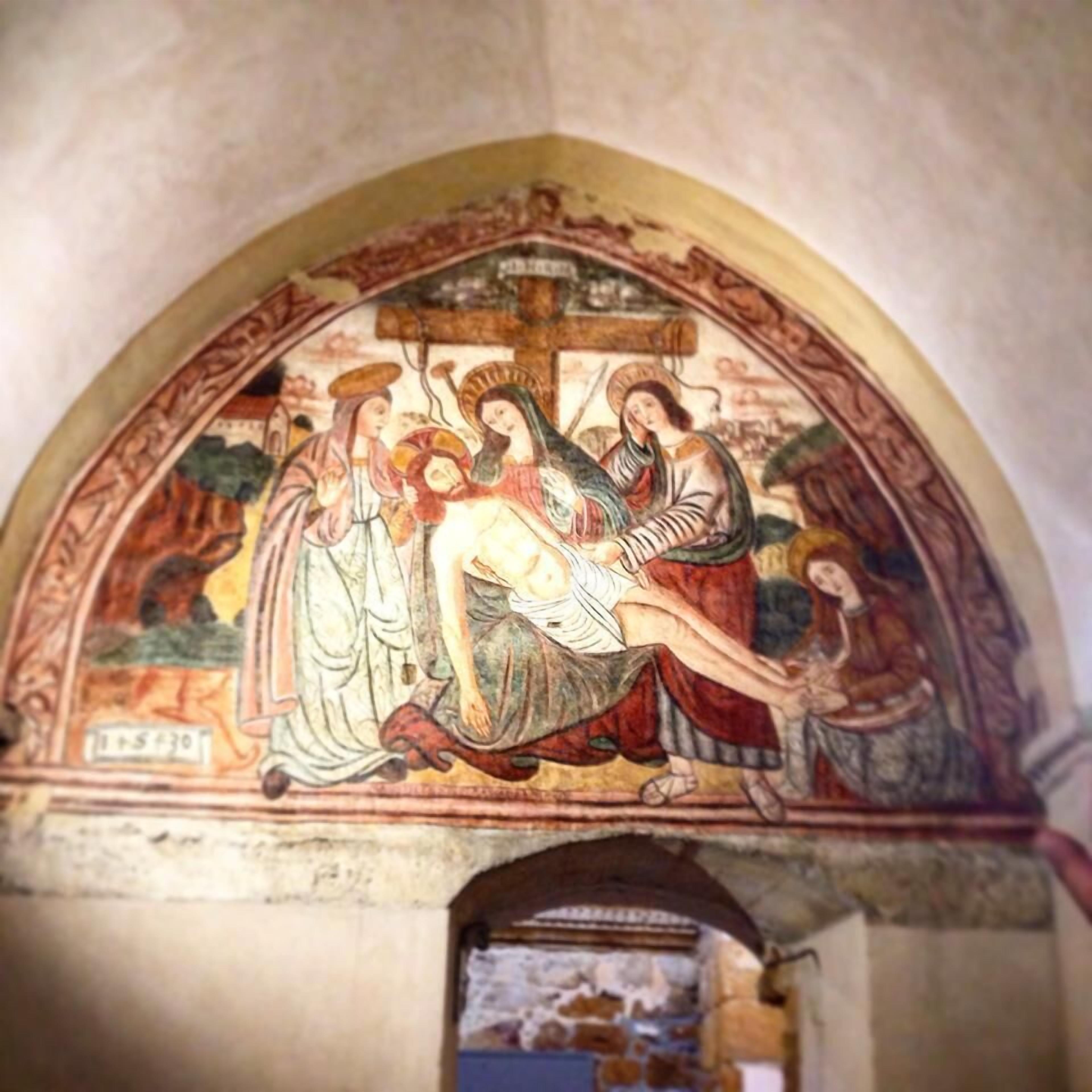 A fresco with a religious scene, a cross, and figures in traditional attire.