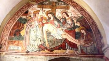 A fresco with a religious scene, a cross, and figures in traditional attire.