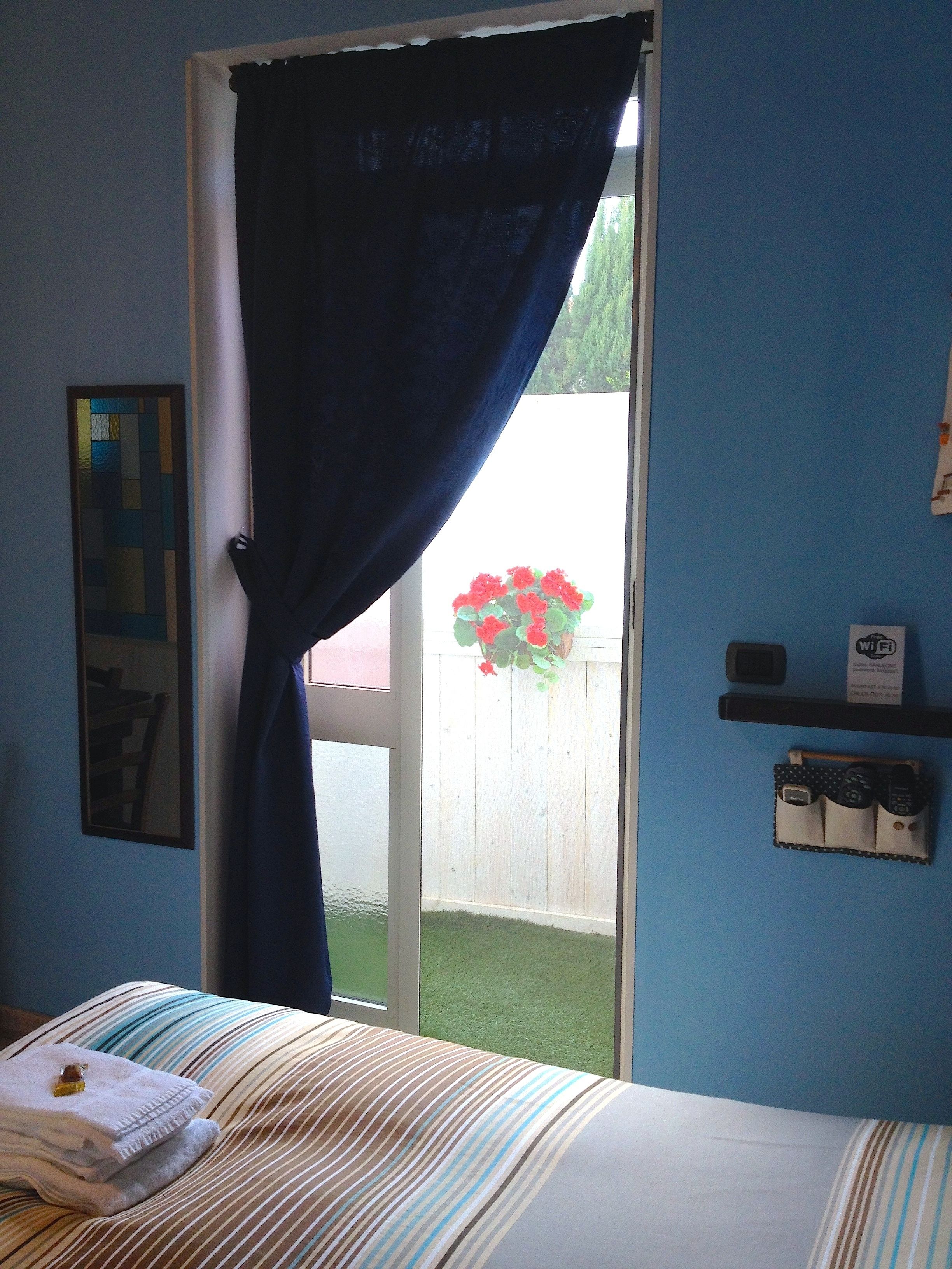 A bedroom with a bed, a window with a curtain, a small plant, and a Wi-Fi sign.