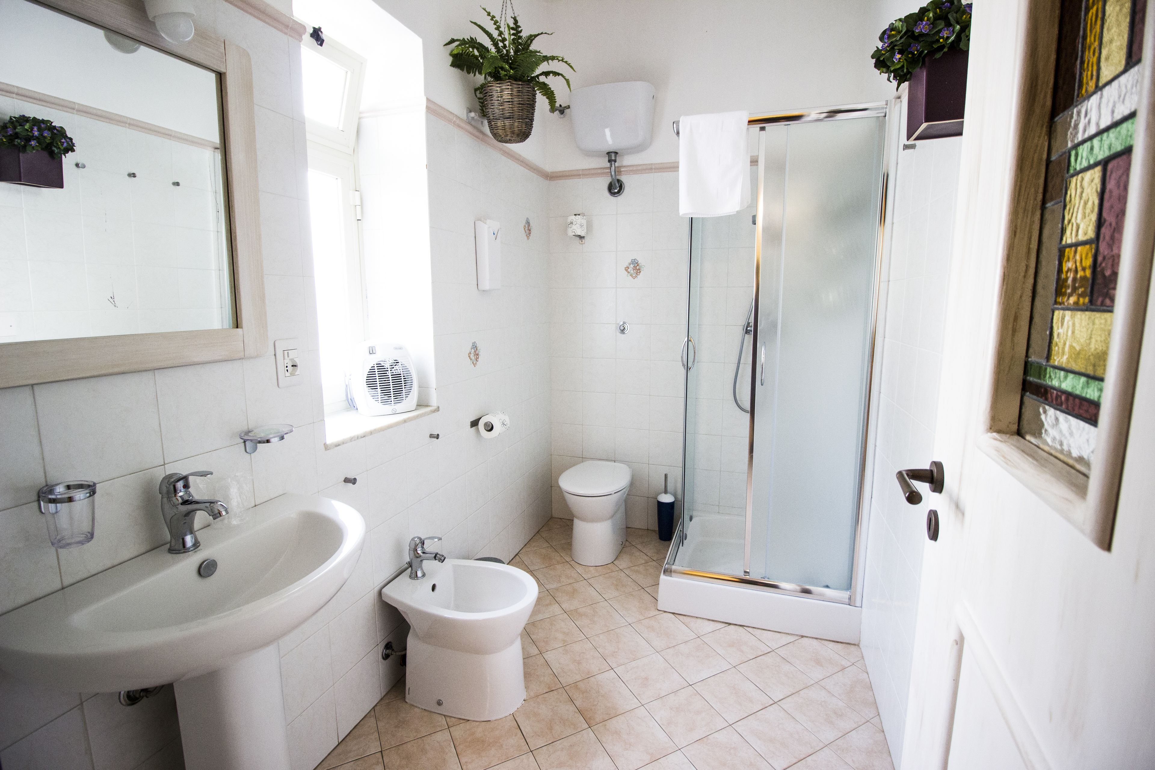 A bathroom with a sink, bidet, toilet, and glass-enclosed shower.