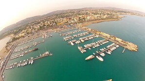 An aerial view of a coastal town with a marina filled with boats, a pier, and residential buildings along the shoreline. - B&B San Leone (Agrigento)
