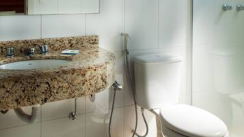 Baño con lavamanos de granito, inodoro y cabina de ducha de vidrio.
