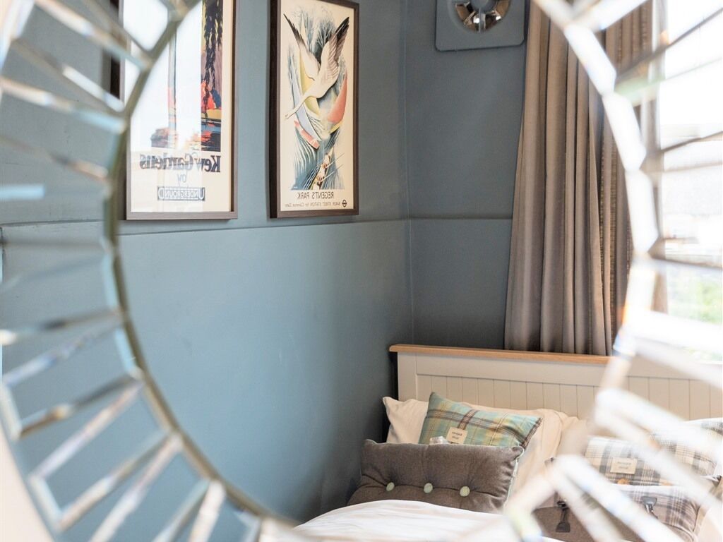 A bedroom with a bed, pillows, and two framed posters on the wall.