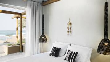 A bedroom with a large bed, white bedding, and two black hanging lamps.