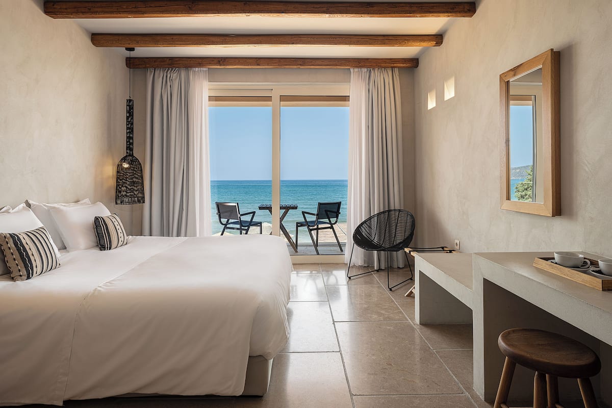 Habitación de hotel con cama, escritorio, silla y vista al mar.