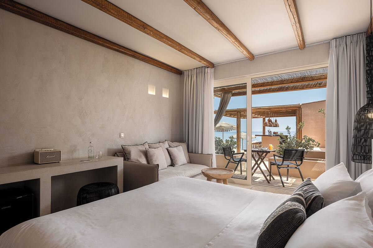 Un dormitorio con una cama grande, un escritorio y vista al mar.