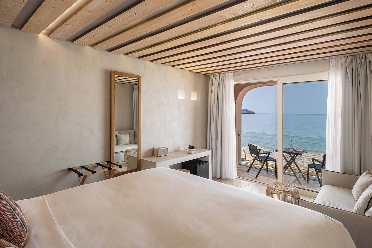 Una habitación de hotel con una cama, un escritorio, una silla y vista al mar.