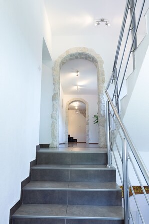 Un escalier surmonté d’une arche en pierre menant à une pièce.
