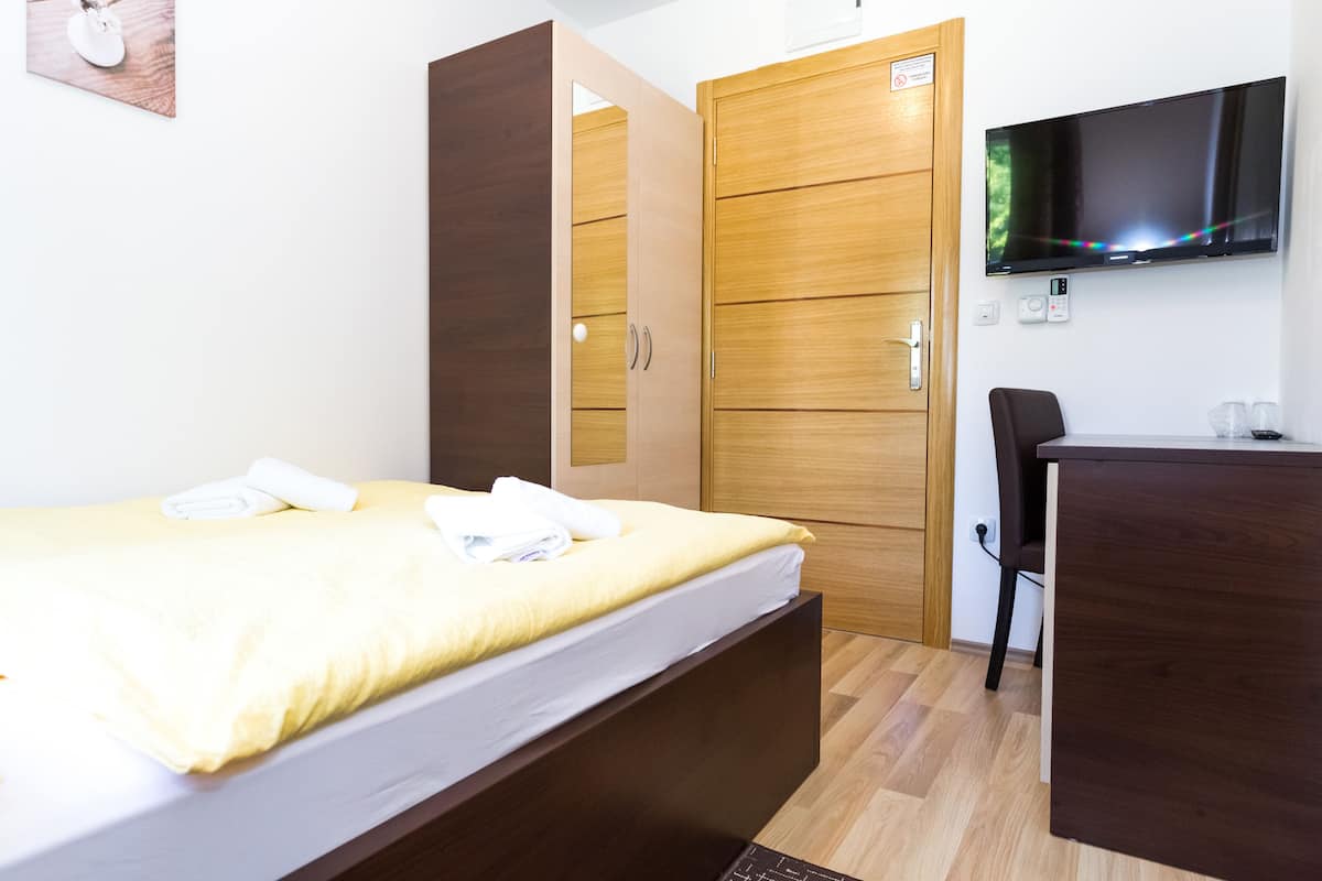 Une chambre à coucher avec un lit, une armoire en bois, un bureau et un téléviseur.